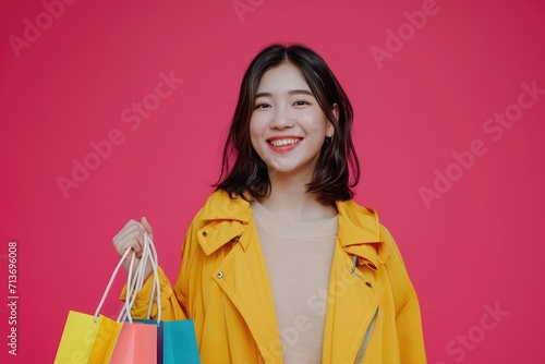 Joyful Asian entrepreneur with shopping bag, confident look, on a dynamic pink background