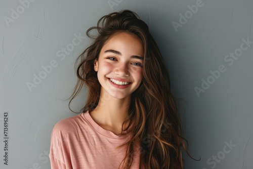 Joyful young woman, perfect smile, grey wall background