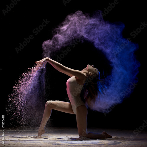 Brunette on her knees in color dust in the dark
