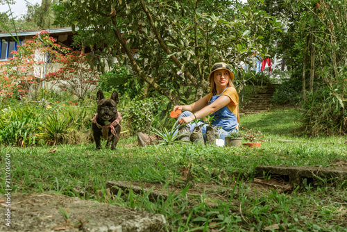 latina woman with her dog planting in beautiful garden 
