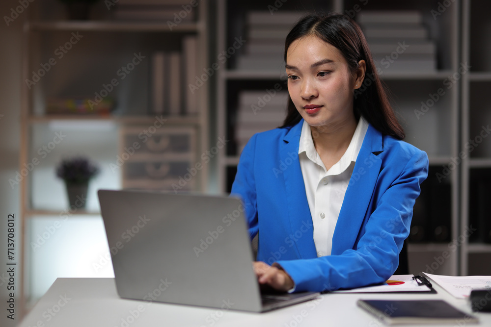 Attractive Asian businesswoman working overtime with documents on desk in office. Attractive Asian businesswoman working overtime with documents on desk in office.