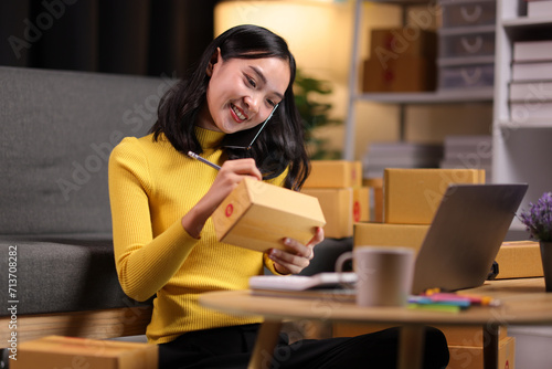 Fotografi A young Asian woman started an online sales business as a part-time job, She is working with shipping boxes to prepare for home delivery of an internet order