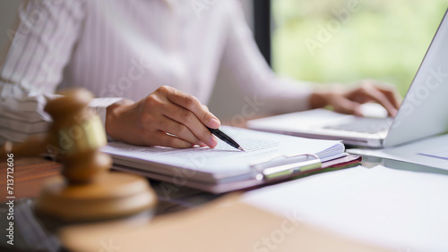 Lawyer woman reading and checking legal agreement of business contract to typing data on laptop photo
