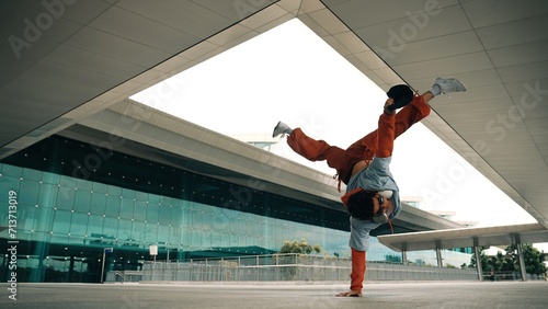 Attractive handsome hipster perform energetic dance while hiphop listen music at building. Professional street dancer move to music while practice energetic performance. Outdoor sport 2024. Sprightly. photo