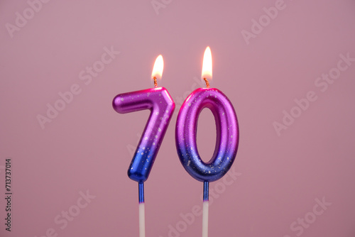 Pink and blue with white spots birthday candles burning on pink background. Number 70.	 photo