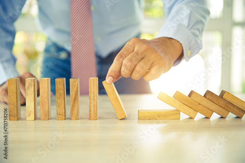 Hand to stop wooden block prevent not falling domino concepts of financial risk management and strategic planning and business challenge plan or safety insurance.