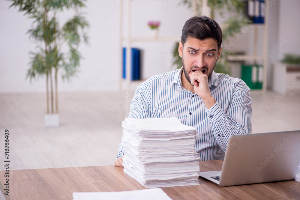 Young male employee and too much work in the office Young male employee and too much work in the office