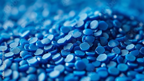 Close-up of shiny blue plastic pellets on a smooth matte surface photo