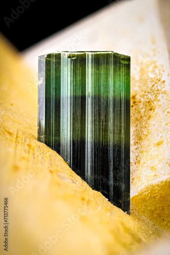 Elbaite verdelite (green tourmaline), on quartz and muscovite isolated on black background. macro detail close-up rough raw unpolished semi-precious gemstone photo