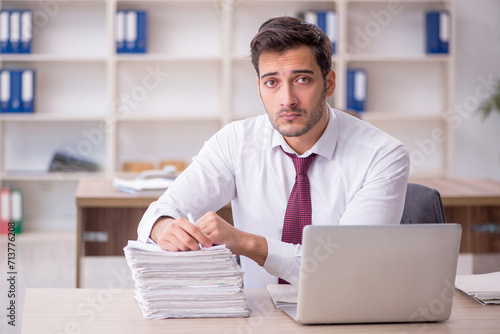 Quadro su tela Young male employee and too much work at workplace