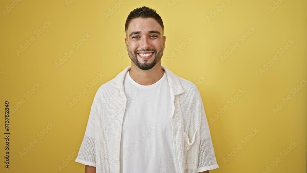 Excited young arab man standing proudly, his cool, confident smile radiating happiness. lucky, cheerful person isolated on a yellow background, exuding natural joy and success. Excited young arab man standing proudly, his cool, confident smile radiating happiness. lucky, cheerful person isolated on a yellow background, exuding natural joy and success.