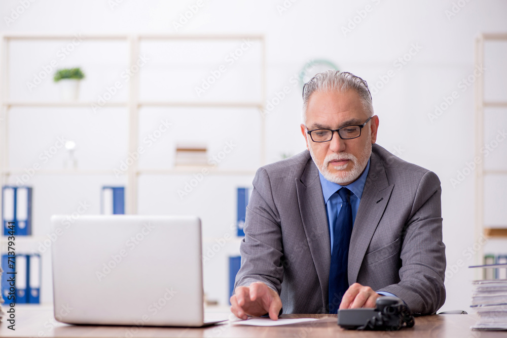 Old male employee working in the office Old male employee working in the office