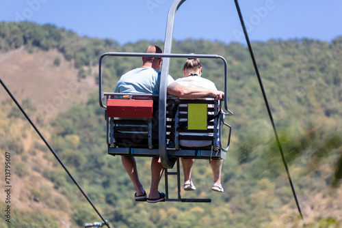 People climb on a ski lift in the mountains against the sky