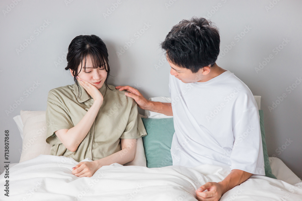 ベッドの上で歯を痛がる妻を心配する夫
ベッドの上で歯を痛がる妻を心配する夫
