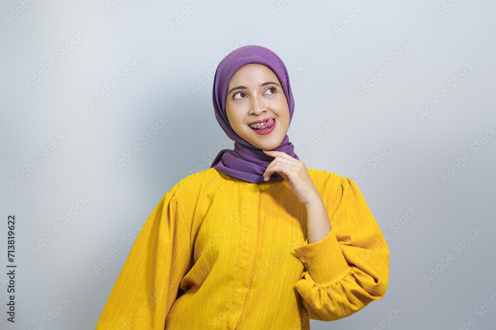 Hungry young Asian Muslim woman looking up at copy space, imaging about delicious food isolated over white background Hungry young Asian Muslim woman looking up at copy space, imaging about delicious food isolated over white background