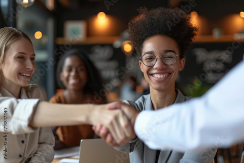 Diverse coworkers celebrate success with handshake and teamwork in corporate workplace