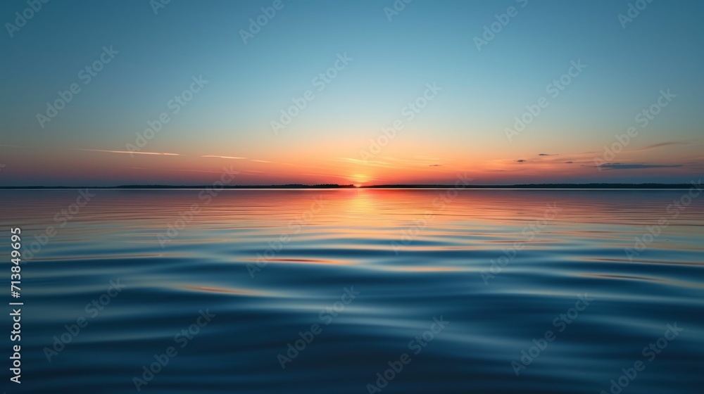 Smooth surface of a calm lake reflecting the sky at sunset, minimal ripples.