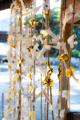 日本の神社の風景、くくりつけられた金と白のおみくじ