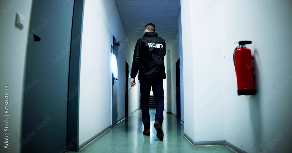 Fototapeta premium Male Security Guard Holding Flashlight Standing In Corridor
