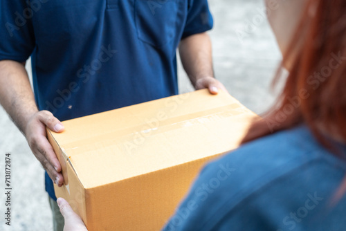 Delivery man holding cardboard boxes. Hand female accepting a delivery boxes of paper containers from courier at home. Signing to get package. Delivery concept. photo