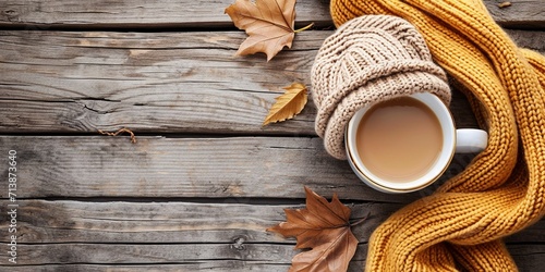 Knitted handmade wool scarf and hat. Autumn or winter womans clothes. Needlework clothes. Hot coffee cup on wooden background