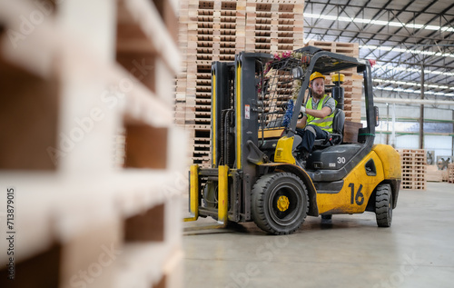 Warehouse worker wears safety helmet driving forklift truck in pallet factory. Skilled male logistic engineer working in shipping storage manufacturing lifting, moving and unloading cargo for delivery photo