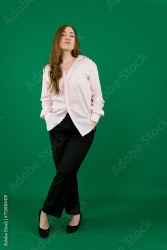 Vertical portrait of a pretty beautiful girl, a happy young woman manager in a jacket and black pants on a green background in studio. Smiling, showing emotions. High quality photo