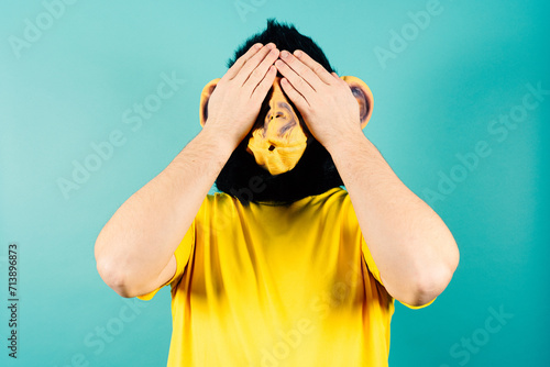 Monkey Masked Person Covering Eyes with Hands, See No Evil Concept photo