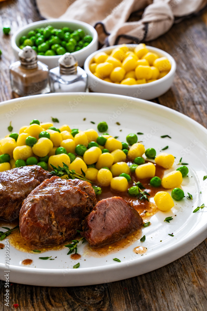 Baked pork cheeks in sauce with gnocchi and green peas on wooden table
Baked pork cheeks in sauce with gnocchi and green peas on wooden table