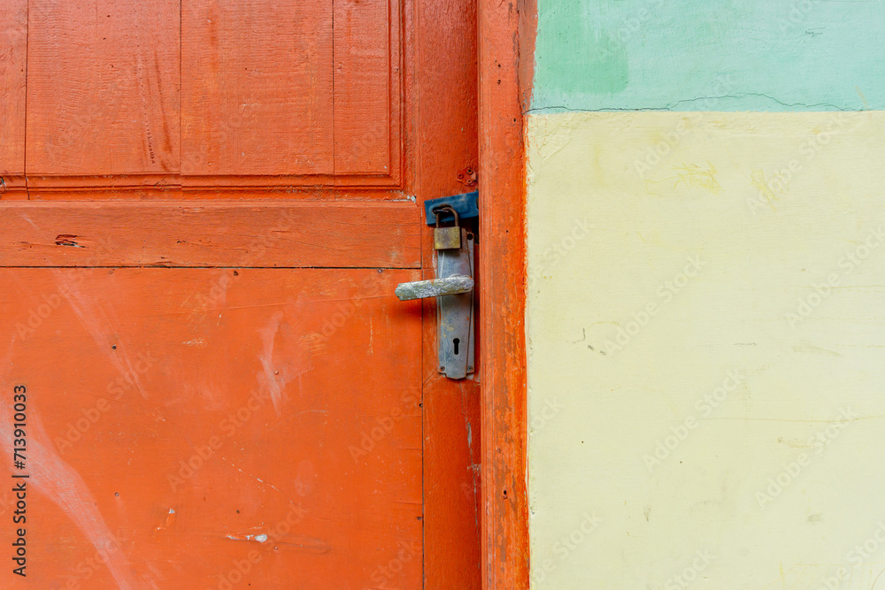 Rusty metal padlock in orange wooden door. Locked door Rusty metal padlock in orange wooden door. Locked door