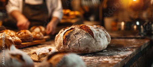Cinematic macro shot of professional artisan baker is showing in camera just prepared fresh whole grains white bread taken out of oven in rustic bakery kitchen. Creative Banner. Copyspace image