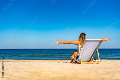 Woman relaxing on beach sitting on sunbed 