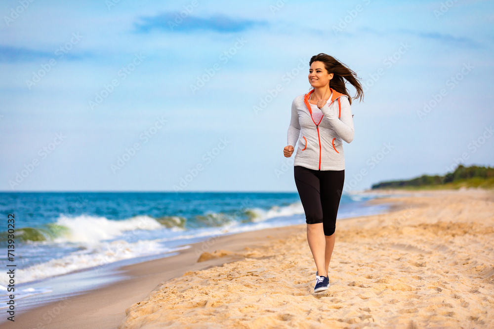 Young beautiful woman running on beach 
