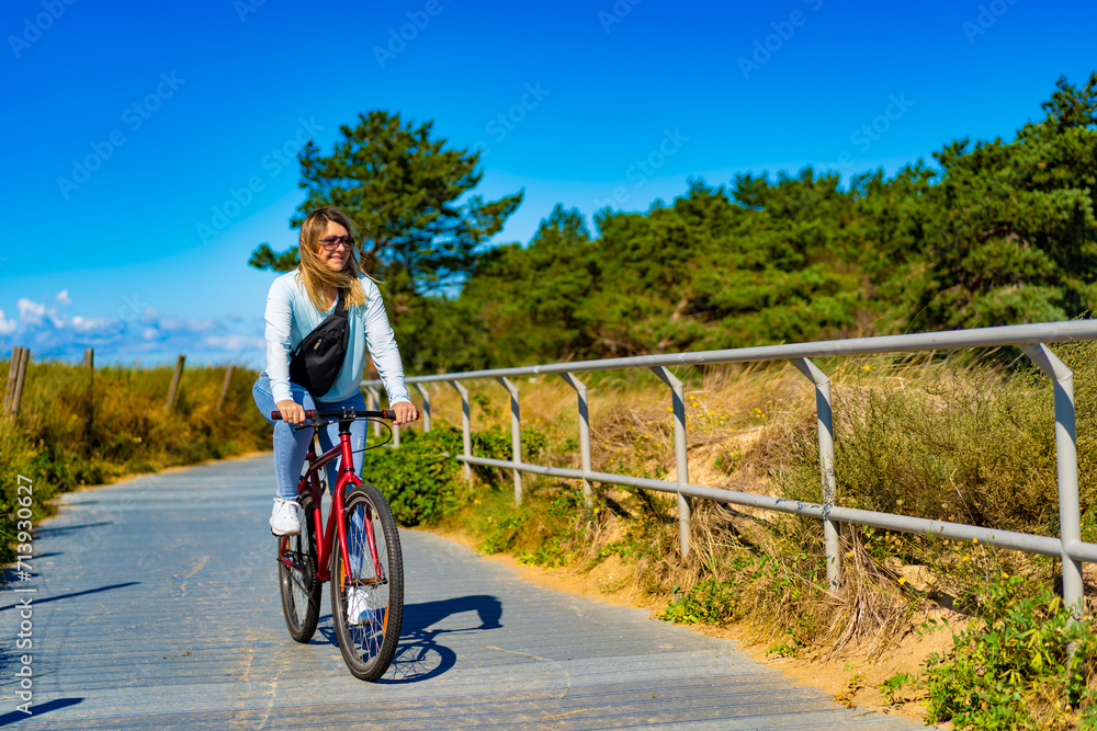 Mid adult woman riding bicycle at seaside

