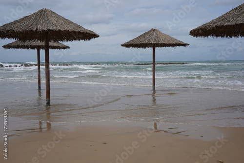 Sandy beach in winter. Waves flood the sandy shore with umbrellas.