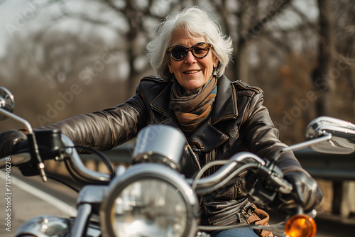 Senior woman Couple On Motorcycle. Mature woman riding a motorbike on the highway. Senior woman rides motorcycle. Woman wearing a leather jacket and gloves © Nataliia_Trushchenko