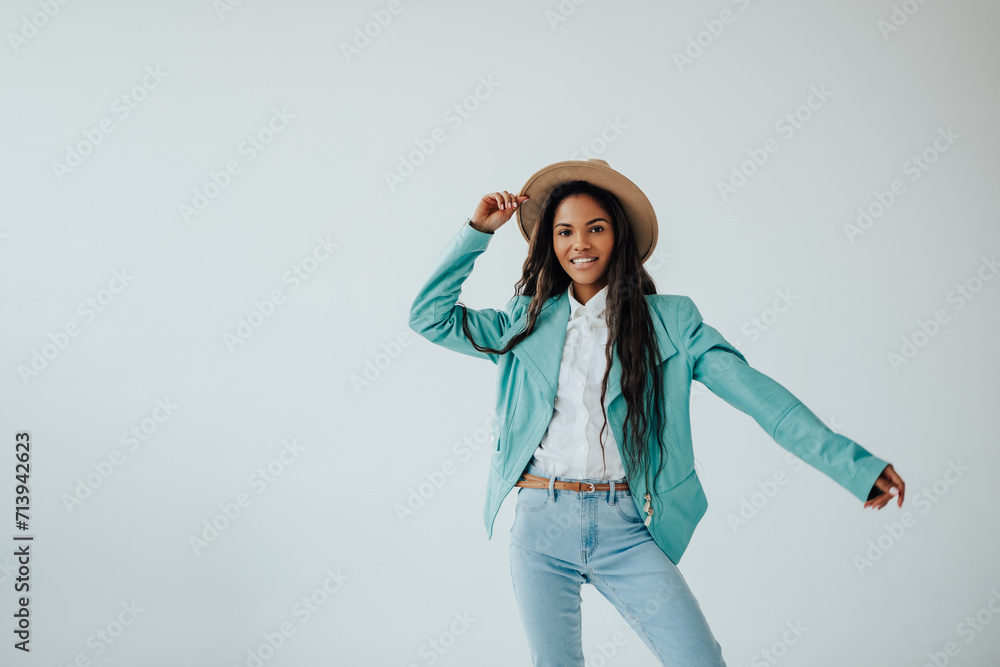 joyful african teenager in a mint jacket and beige hat posing in a spacious bright room. joyful african teenager in a mint jacket and beige hat posing in a spacious bright room.