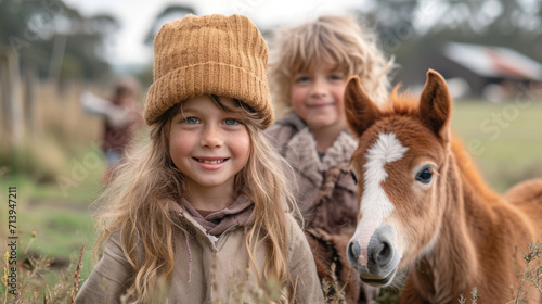 Joyful children walking with foal on farm: girl and boy with small horse © Dmitry