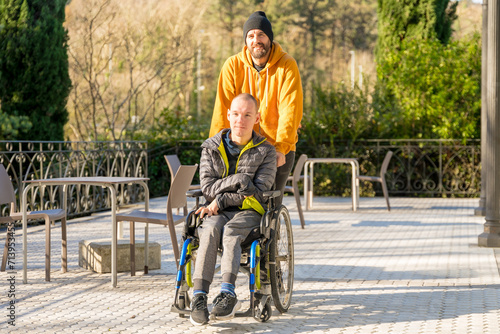 Disabled man with wheelchair and friends strolling in a park