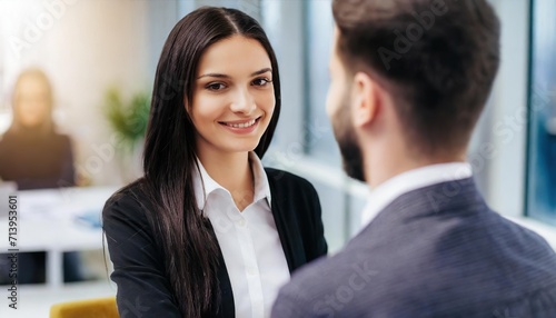 A professional conversation between a smiling young woman and a man in a modern office setting