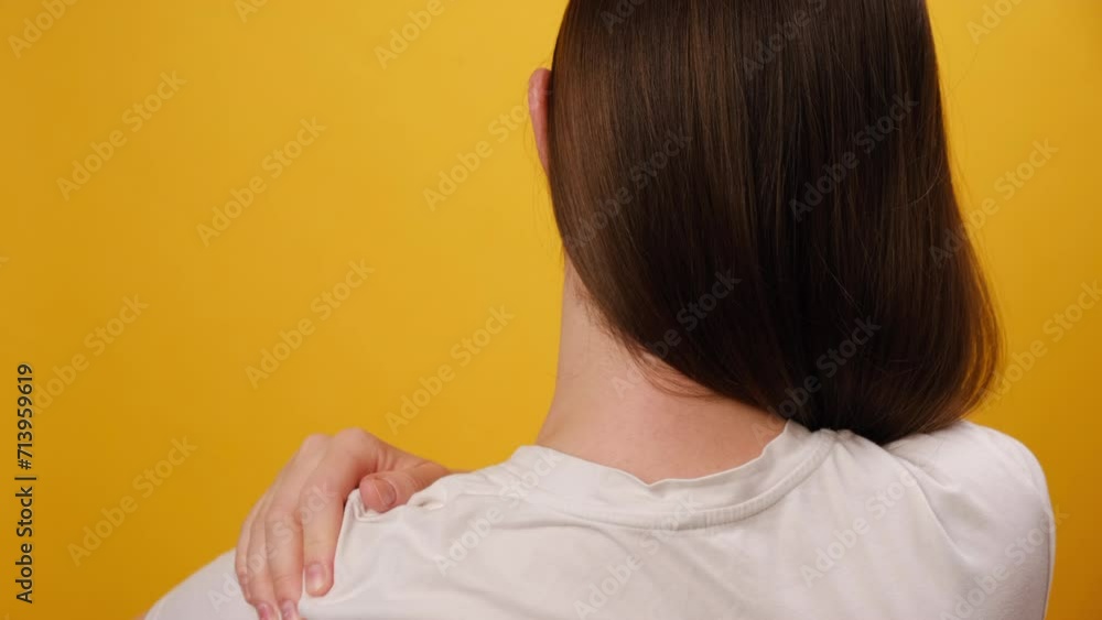 Close up of unhealthy young woman has shoulder pain, isolated over yellow background. Female holding painful shoulder with another hands. People with body-muscles problem, Healthcare And Medicine Close up of unhealthy young woman has shoulder pain, isolated over yellow background. Female holding painful shoulder with another hands. People with body-muscles problem, Healthcare And Medicine