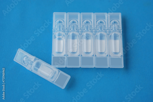 Single use artificial tear lubricant eye drops containers, tubes, isolated on blue background. Concept,medical products for dry eyes or eyes disease treatment. Use under doctor prescription.  