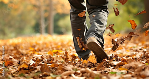 Low section of man walking through autumn leaves in park, closeup