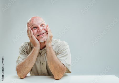 Fotografi Elder's tender daydreaming, hands cupping smiling face