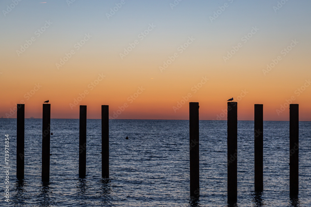 The architectural columns of Brighton's West Pier, with a sunset sky behind The architectural columns of Brighton's West Pier, with a sunset sky behind