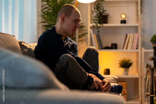 Disabled man sitting alone in the sofa with sad expression photo