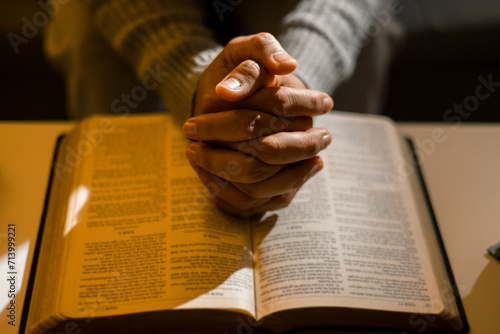 Human person hands worship, Concept of praying to God. Christian religious woman praying at night sitting on couch in living dark room at home. Female prayer with holy bible. Lady thanksgiving night