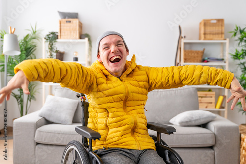 Happy disabled man in wheelchair laughing at camera at home photo