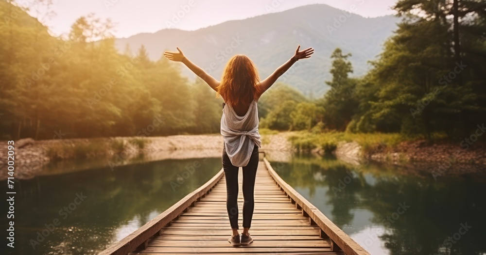 Naklejka premium A Young Woman's Uplifting Moment with Arms Raised, Set Against Nature's Backdrop