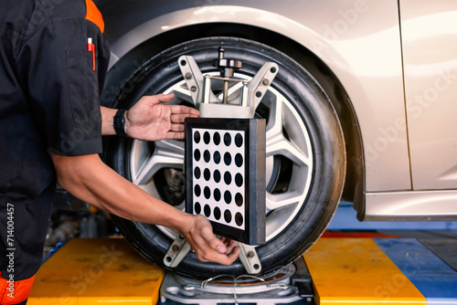  Close-up of car mechanics installing sensors during suspension adjustment and automobile wheel alignment. Car wheel alignment is in progress. auto camber toe check fixing. photo